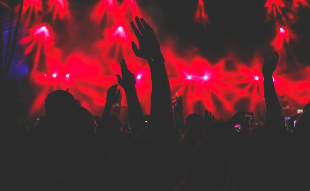 Pubblico in festa con le mani alzate sotto una luce rossa